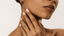 a hand placed on a woman's neck with short neutral coloured square nails