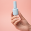 Hand holding a gel break bottle against a pink background