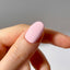 Close-up of a hand with a pink nail on a neutral background