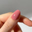 Close-up of a hand with a pink nail on a neutral background