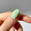 Close-up of a hand with a light green nail polish on a neutral background