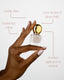 Hand holding a small bottle with gold cap, surrounded by text about product features on a light background