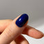 Hand with a navy glittery nail on a neutral background