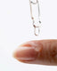 Dropper with clear liquid dripping onto a person's finger against a white background