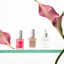 Three bottles of NONICURE nail care products with pink calla lilies on a white background