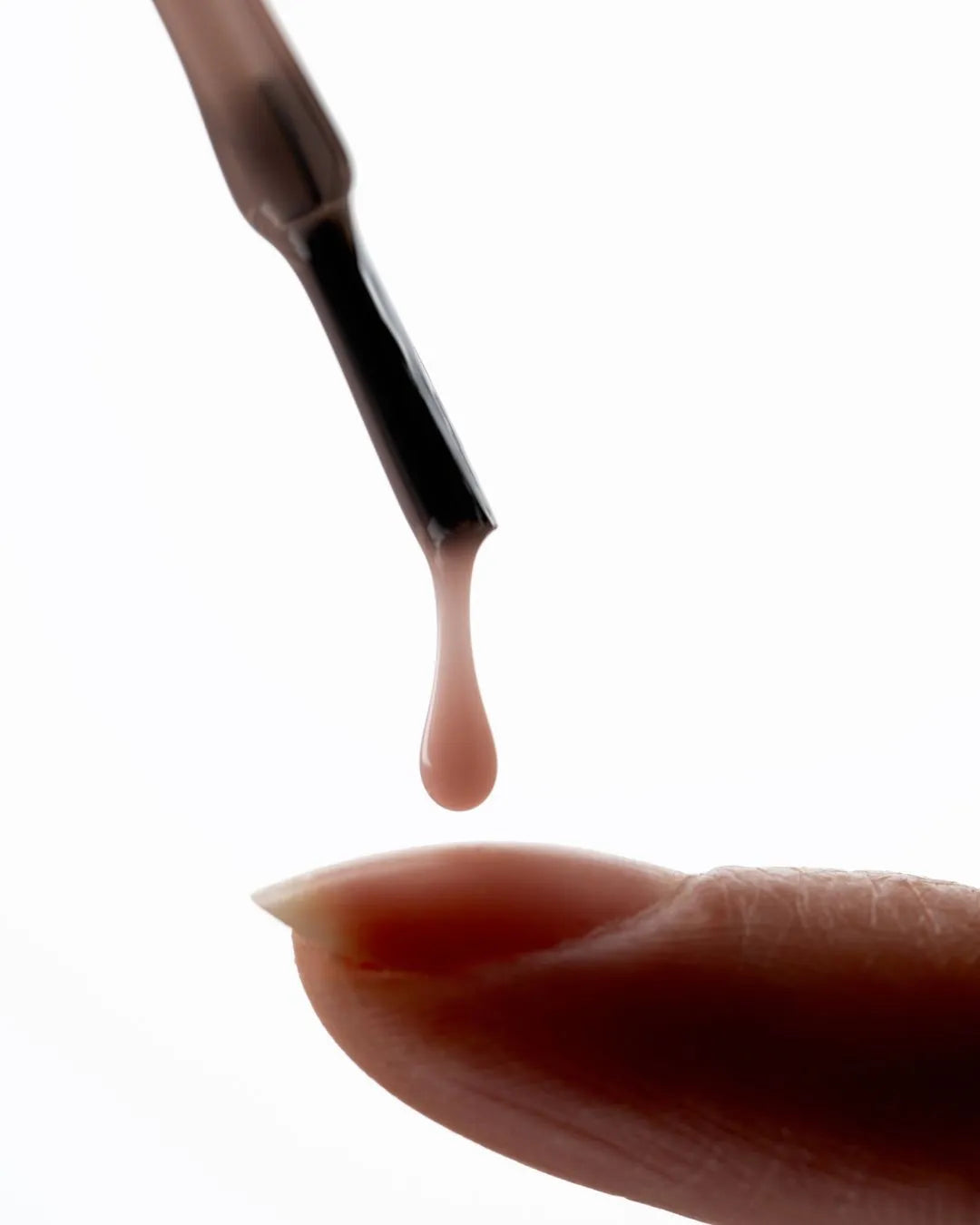 Close-up of a lip brush with a drop of lip color on a white background
