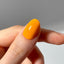 Hand with a bright orange nail against a neutral background
